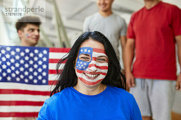 Lächelnder Fan mit aufgemaltem Gesicht der amerikanischen Flagge bei Sportveranstaltung im Stadion