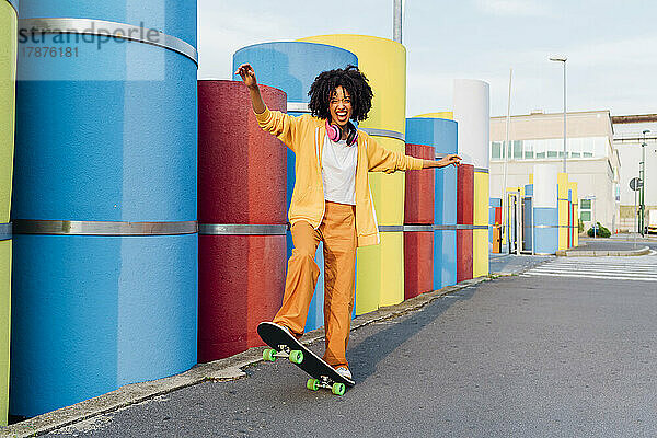 Fröhliche Frau genießt Skateboard an bunten Rohren