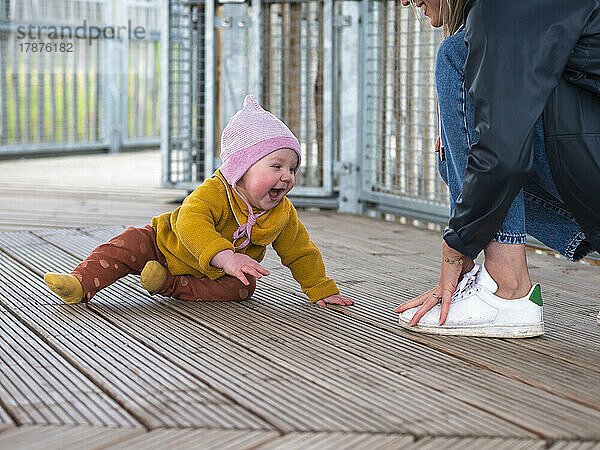 Glückliches kleines Mädchen  das mit Mutter auf der Promenade spielt