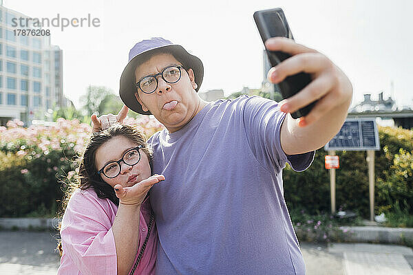 Verspielter Bruder und Schwester machen Grimassen und machen Selfies mit dem Smartphone