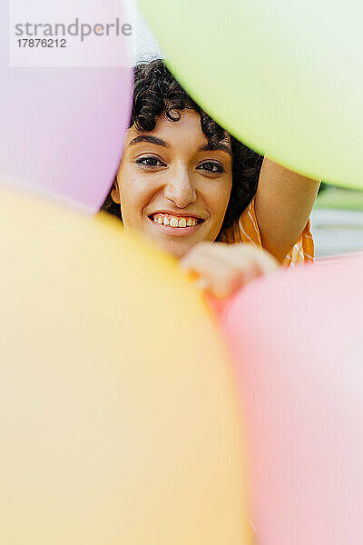 Glückliche Frau hinter bunten Luftballons