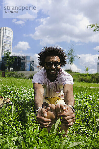 Fröhlicher Mann dehnt sich auf Gras im Park