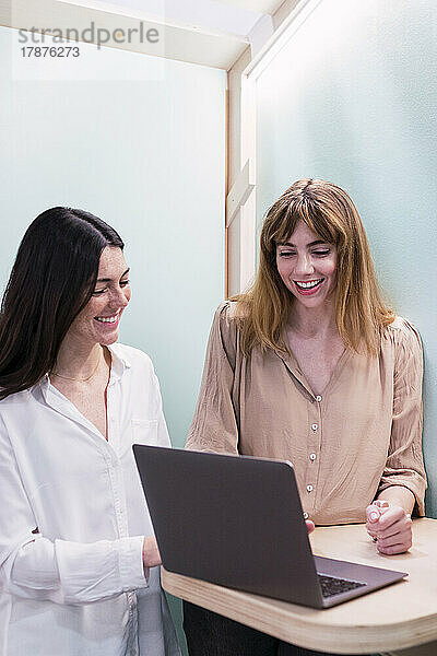 Zwei glückliche Geschäftsfrauen mit Laptop im Büro