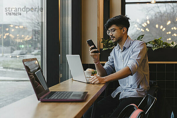 Junger Freiberufler nutzt Smartphone im Café