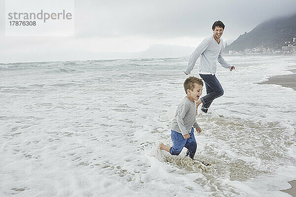 Vater läuft mit seinem Sohn am Strand