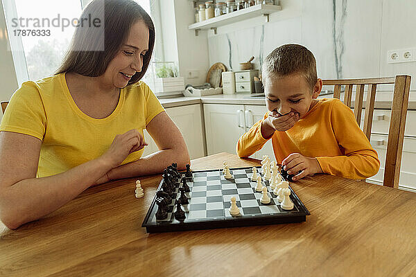 Lächelnde Mutter und Sohn spielen zu Hause Schach