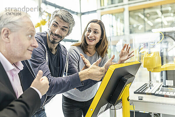 Glückliche Kollegen geben Daumen hoch in der Roboterfabrik