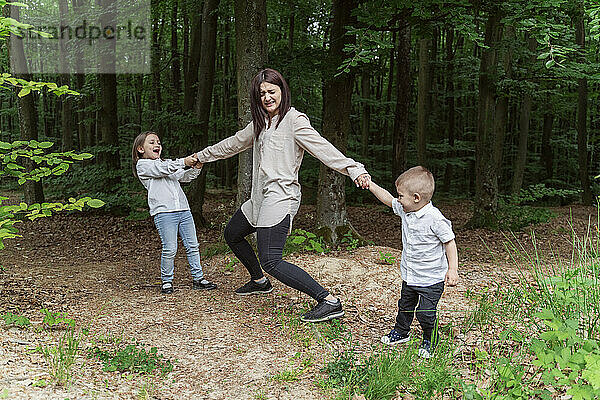 Kinder spielen mit Mutter im Wald