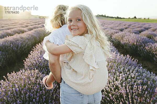 Woman giving piggyback ride to daughter in lavender field