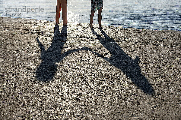 Schatten eines Paares  das Händchen hält und auf dem Pier steht