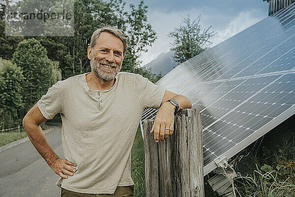 Lächelnder reifer Mann  der neben einem Solarpanel auf der Straße steht