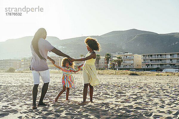 Vater und Töchter spielen am Strand Ring um Rosy