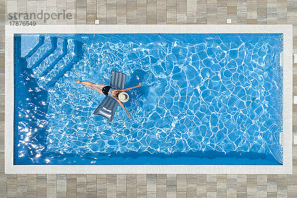 Frau schwimmt mit Poolfloß im Pool