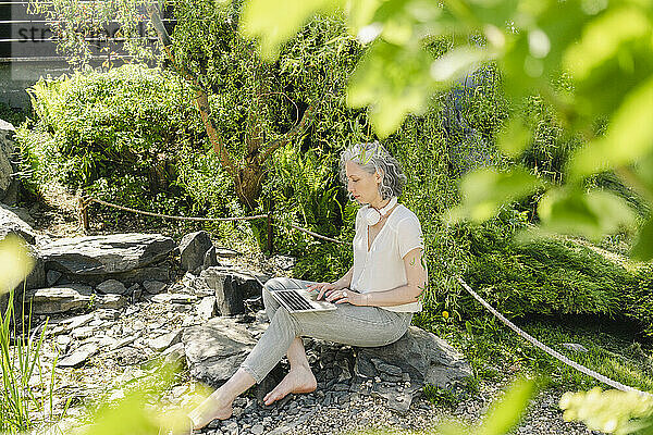 Freiberufler arbeitet am Laptop bei Pflanzen im Park