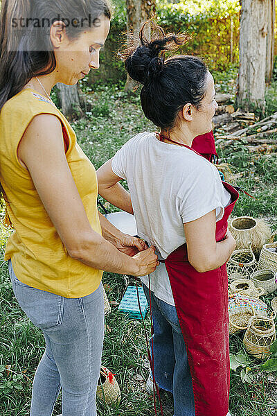 Frau hilft Freundin  Schürze im Garten zu tragen