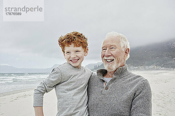 Glücklicher Großvater  der seinen Enkel am Meer trägt