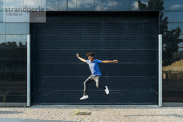 Lächelnder Mann springt vor Gebäude