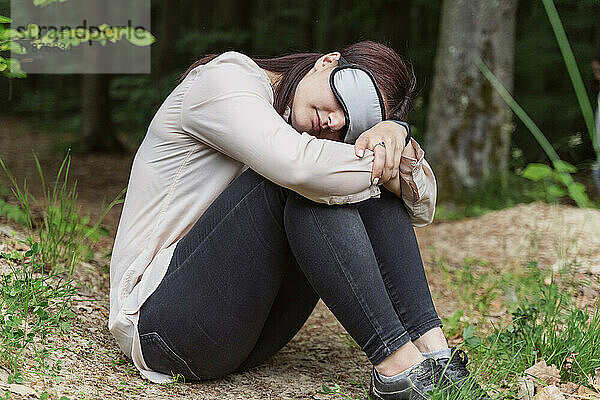 Frau mit Schlafmaske sitzt im Wald