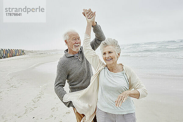 Glückliches älteres Paar tanzt am Strand