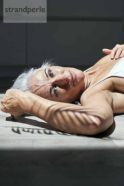 Mature woman lying down on floor at home