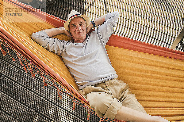 Senior man wearing hat relaxing in hammock