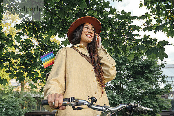 Glückliche Frau  die im Park mit dem Fahrrad telefoniert