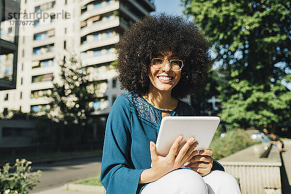 Lächelnder Freiberufler mit digitalem Tablet an einem sonnigen Tag