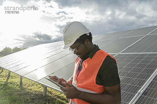 Mann mit Helm benutzt Tablet-PC an Solarstation