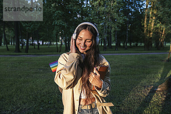 Frau genießt es  im Park Musik über Kopfhörer zu hören