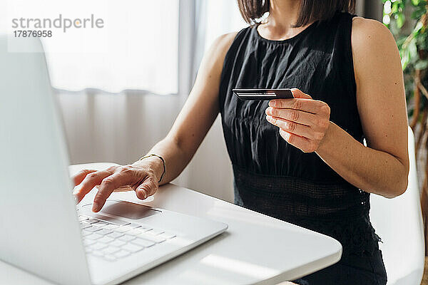 Frau mit Kreditkarte beim Online-Einkauf per Laptop