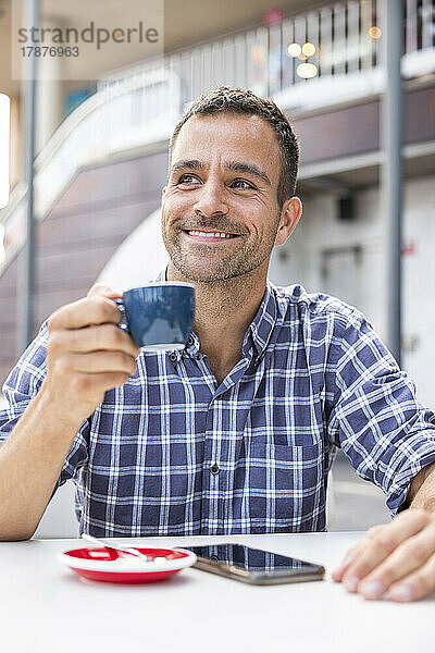 Lächelnder reifer Mann trinkt Kaffee am Straßenkaffee