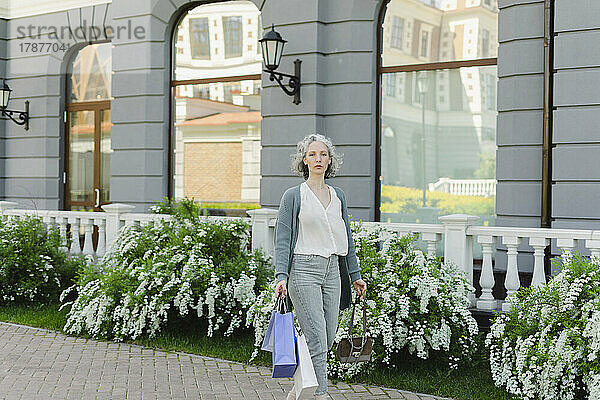 Frau mit Einkaufstüten vor Gebäude