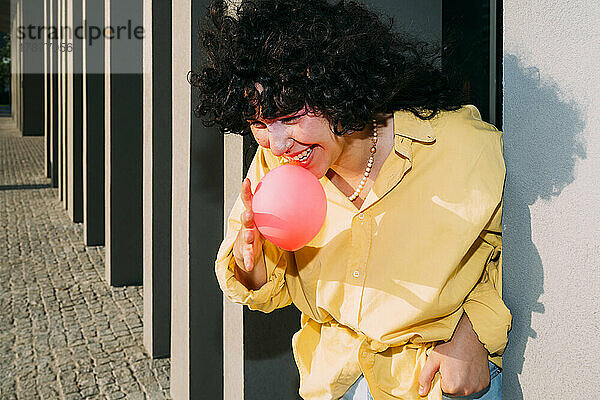 Lächelnde Frau bläst an einem sonnigen Tag Kaugummi in die Säule