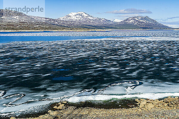 Schweden  Norrbottens län  Langzeitbelichtung von schwimmendem Eis im Akkajaure-Stausee mit Bergen im Hintergrund
