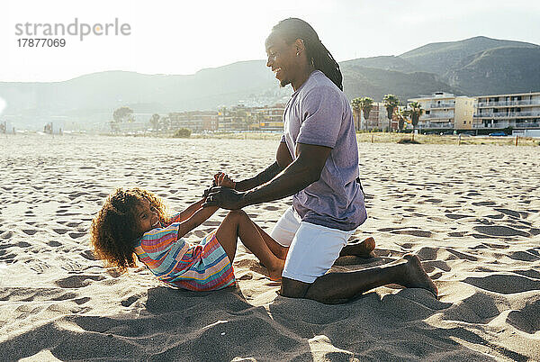 Vater spielt mit Tochter am Strand