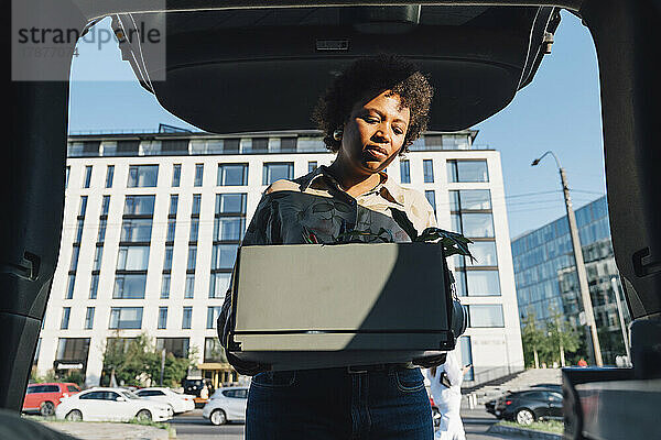 Geschäftsfrau mit lockigem Haar  Aufbewahrungsbox im Kofferraum