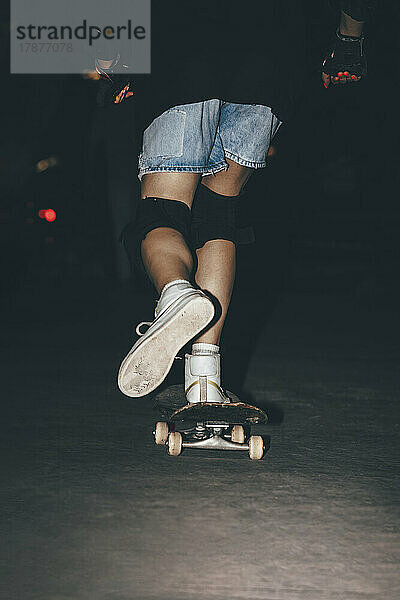 Woman skateboarding in park at night