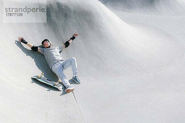 Man with skateboard resting in skatepark
