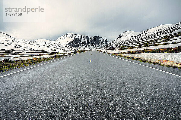 Norwegen  Innlandet  Norwegische Nationalstraße 15  die sich zwischen schneebedeckten Hügeln erstreckt