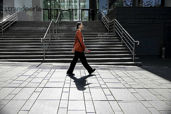 Geschäftsfrau läuft auf Fußweg in der Nähe eines Bürogebäudes