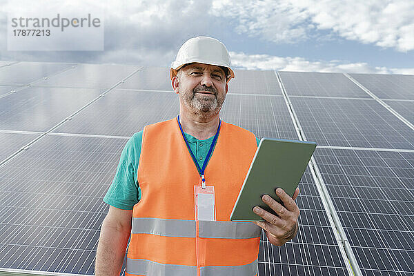 Ingenieur mit Tablet-PC vor Solarpaneelen