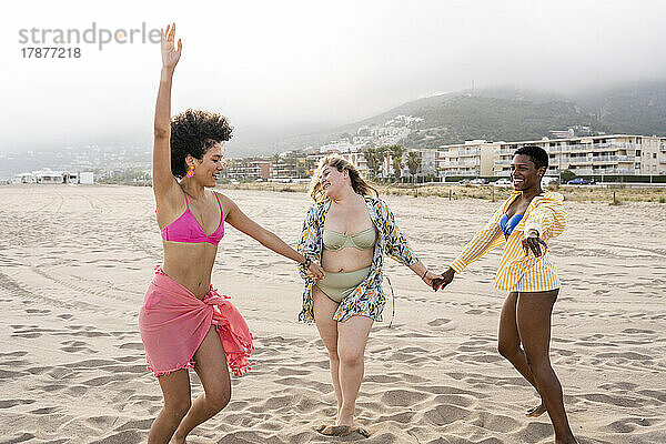 Gemischtrassige Frauen tanzen am Strand