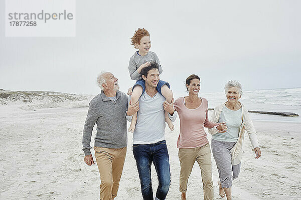 Glückliches Paar verbringt schöne Zeit am Strand mit Sohn und Großeltern
