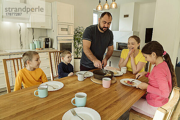 Mann serviert Familie zu Hause Frühstück