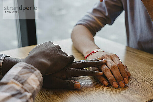 Mann berührt die Hand eines Freundes am Tisch im Café