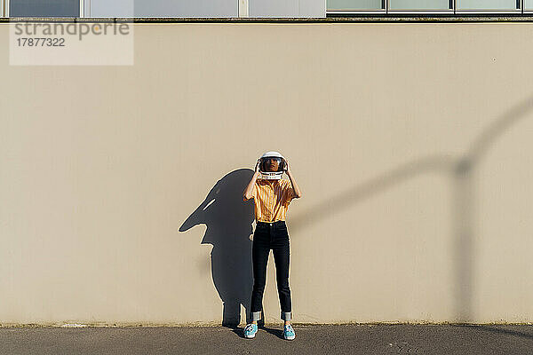 Frau mit Weltraumhelm steht vor der Wand