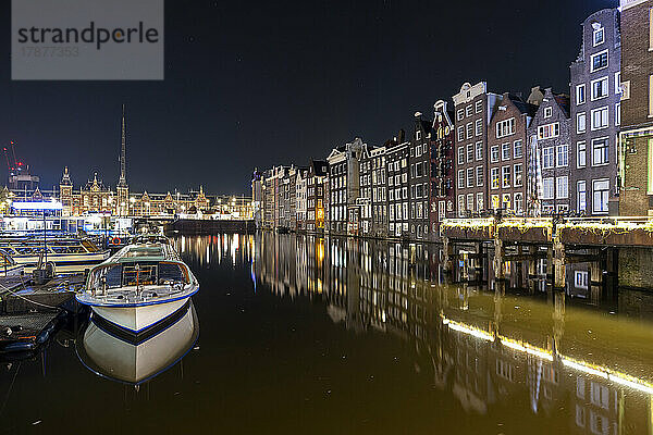 Niederlande  Nordholland  Amsterdam  Langzeitbelichtung des Damrak-Kanals bei Nacht mit Reihenhäusern im Hintergrund