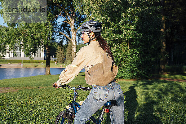 Frau fährt an sonnigem Tag Fahrrad im Park