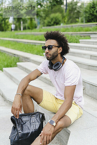 Man wearing sunglasses sitting with backpack on steps
