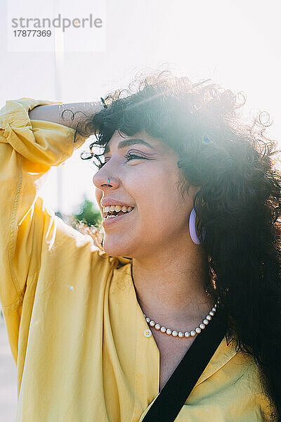 Smiling woman with hand in hair on sunny day